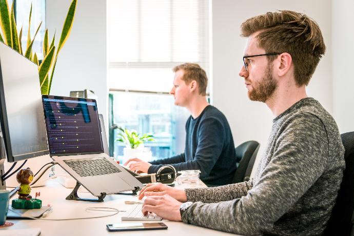 IT Network Support Team responding to technical issues and alerts in front of their laptop computers with cell phones engaging with customers